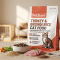 A stand-up pouch of PetStore Turkey & Brown Rice Cat Food stands on a wooden surface in a softly blurred indoor setting. The package is white with orange-red panels and a photo of a tabby cat.